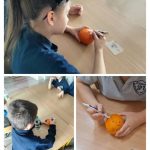 Dzieci siedzą przy stole i rysują markerami po pomarańczach podczas zajęć w klasie.