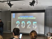 Na ekranie projektora w sali konferencyjnej można zobaczyć II Poznańskie Forum Wolontariatu Szkolnego 2025.