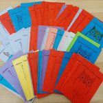 Kolorowe książeczki z ilustrowanymi okładkami przedstawiającymi sowy, ułożone wachlarzowato na drewnianej powierzchni.