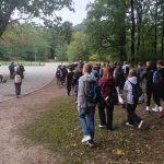 Grupa uczniów idzie ścieżką w parku otoczonym drzewami.