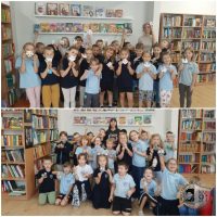 Dwie grupy uśmiechniętych dzieci trzymają papierowe rękodzieła w kolorowej bibliotece.