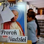 Chłopiec przechodzi obok plakatu papieża Jana Pawła II z napisem Prorok Nadziei na szkolnym korytarzu.