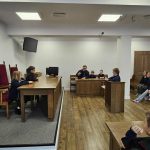 Dzieci odgrywają scenę sądową, siedząc przy biurkach i ławkach w pozorowanej sali sądowej.