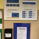 Tablice informacyjne i skrzynka pocztowa na ścianie z listą zasad, numerami infolinii i skrzynką na sugestie.