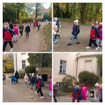 Dzieci spacerują razem na zewnątrz jesienią, ubrane w kurtki i czapki, z drzewami i budynkami w tle.