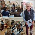 Autor przemawia do studentów w bibliotece; trzyma książkę, podczas gdy publiczność uważnie słucha.