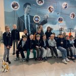 Grupa dzieci pozuje w pomieszczeniu przed wystawą ścienną o tematyce naukowej, z zabawkowym lisem na podłodze.