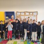 Grupa uczniów i nauczyciel uśmiechają się i pozują razem w kolorowej klasie.