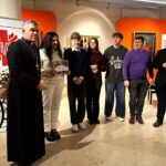 Grupa ludzi stoi razem w pomieszczeniu podczas rozdania nagród, a dwóch mężczyzn trzyma certyfikat.