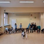 Dzieci w klasie czołgają się po podłodze, uczestnicząc w zajęciach grupowych lub ćwiczeniach.