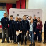 Grupa uczniów stoi w pomieszczeniu przed wystawą zorganizowaną przez fundację edukacyjną.