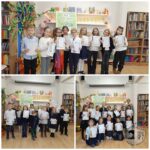 Dzieci pozują z certyfikatami w bibliotece, stojąc przed półkami z książkami i kolorowymi dekoracjami.