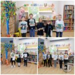 Dzieci trzymające książki stoją w bibliotece przed półkami i kolorową tablicą.