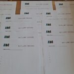 Kilka wydrukowanych arkuszy Spelling Bee 2025/2026 z logo ABC rozłożonych na stole.