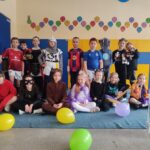 Grupa dzieci w kostiumach pozuje w pomieszczeniu z balonami na podłodze przed nimi.