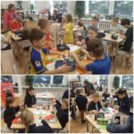 Dzieci w klasie wykonujące prace plastyczne i rękodzielnicze przy stolikach pod nadzorem nauczycieli.