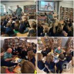 Autor czyta i podpisuje książki dla młodych uczniów podczas wydarzenia w bibliotece szkolnej, otoczony książkami.