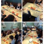 Dzieci siedzą przy stołach, przygotowując pizze, smarując je sosem i dodając dodatki do ciasta w restauracji.