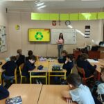 Nauczyciel prezentuje recykling uważnym uczniom w klasie z grafiką przedstawiającą recykling.