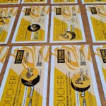 Rzędy żółto-białych wydrukowanych kuponów na wydarzenie szachowe są starannie ułożone na drewnianym stole.