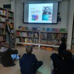 Dzieci oglądają w klasie prezentację o Roaldzie Dahlu, z książkami wyświetlanymi na dużym ekranie.