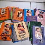 Kolorowe, ręcznie robione kartki z religijnymi obrazkami i polskimi zwrotami, rozłożone na białej powierzchni.