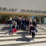 Grupa dzieci pozujących i uśmiechających się na schodach przed budynkiem Muzeum Narodowego.