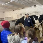 Farmer pokazujący krowy dzieciom w oborze.