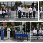 Uczniowie i nauczyciele stoją przed szkołą podczas ceremonii wręczenia nagród, trzymając certyfikaty i trofea.