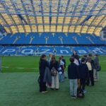 Grupa uczniów stojąca na boisku wewnątrz poznańskiego stadionu.