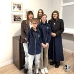 Dwoje dorosłych i troje dzieci pozujących do zdjęcia grupowego w biurze.