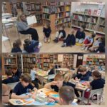 Nauczyciel czyta młodym uczniom w bibliotece, a uczniowie pracują nad projektami plastycznymi przy ławkach.
