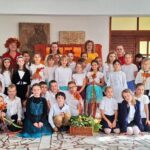 Duża grupa uczniów szkoły podstawowej i nauczycieli pozujących razem w pomieszczeniu.