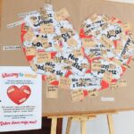 Tablica ogłoszeń z papierowym sercem pokrytym karteczkami samoprzylepnymi z odręcznymi wiadomościami w języku polskim.