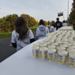 Na stole stało wiele papierowych kubków z napisem Aquanet poleca, a za nimi stali wolontariusze.
