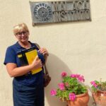 Kobieta trzyma podręcznik do nauki języka hiszpańskiego formatu A1 przed tablicą z napisem Malaca Instituto.